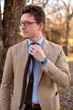 Tan cotton suit with blue oxford shirt and brown knit tie with dark rinse jeans